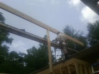Carpenter setting a ridge beam over a new addition frame — Ice Dam Removal by Roofing Brothers in Pensacola