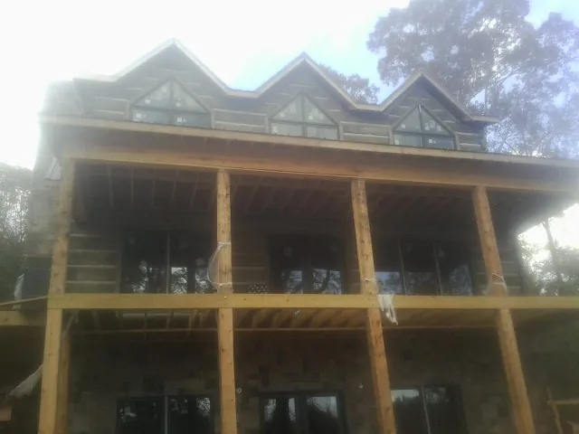 Dormers and porch framing on a large log home under construction — Roof Coating work by our crew in Pensacola