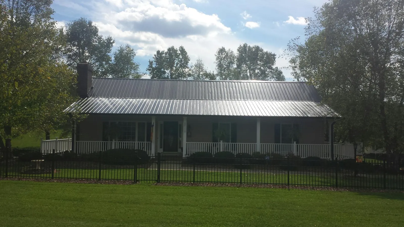 Gray metal roof on a brick ranch with a full width front porch — Gutter Guard Installation work by our crew in Pensacola