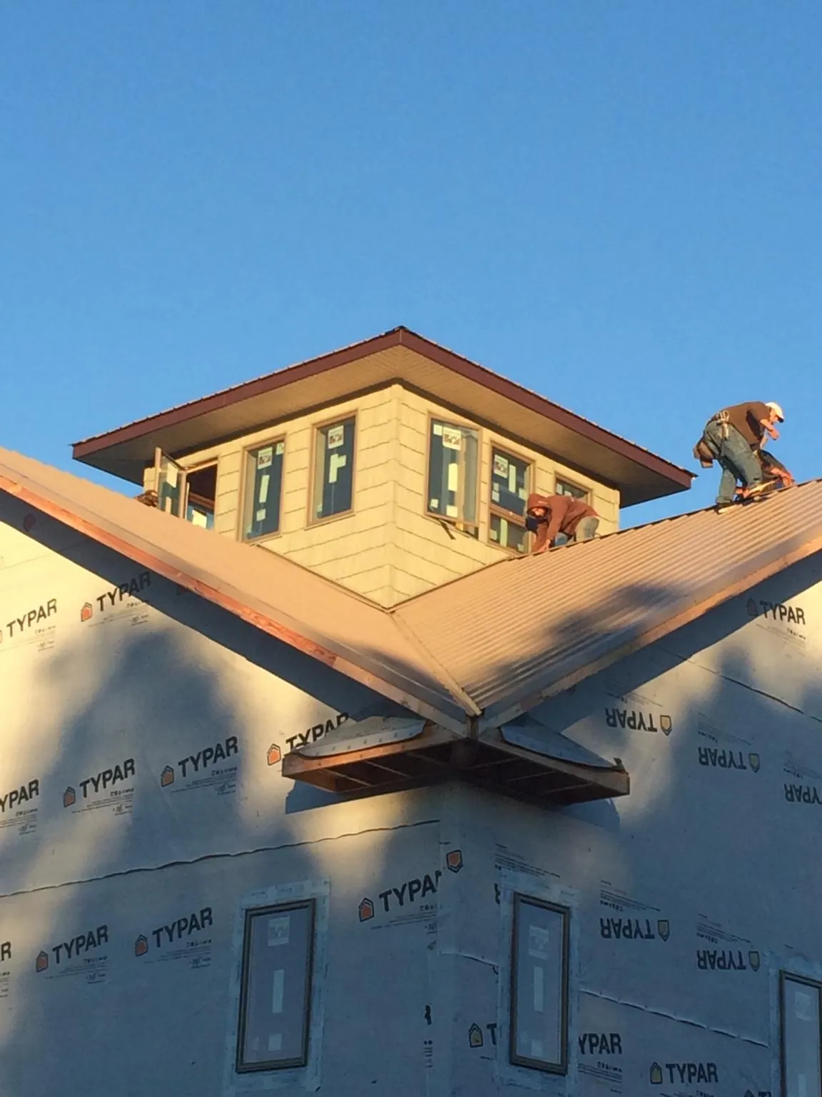 Roofers working around a rooftop cupola on a new metal roof at sunset — Roof Waterproofing in Pensacola by Roofing Brothers